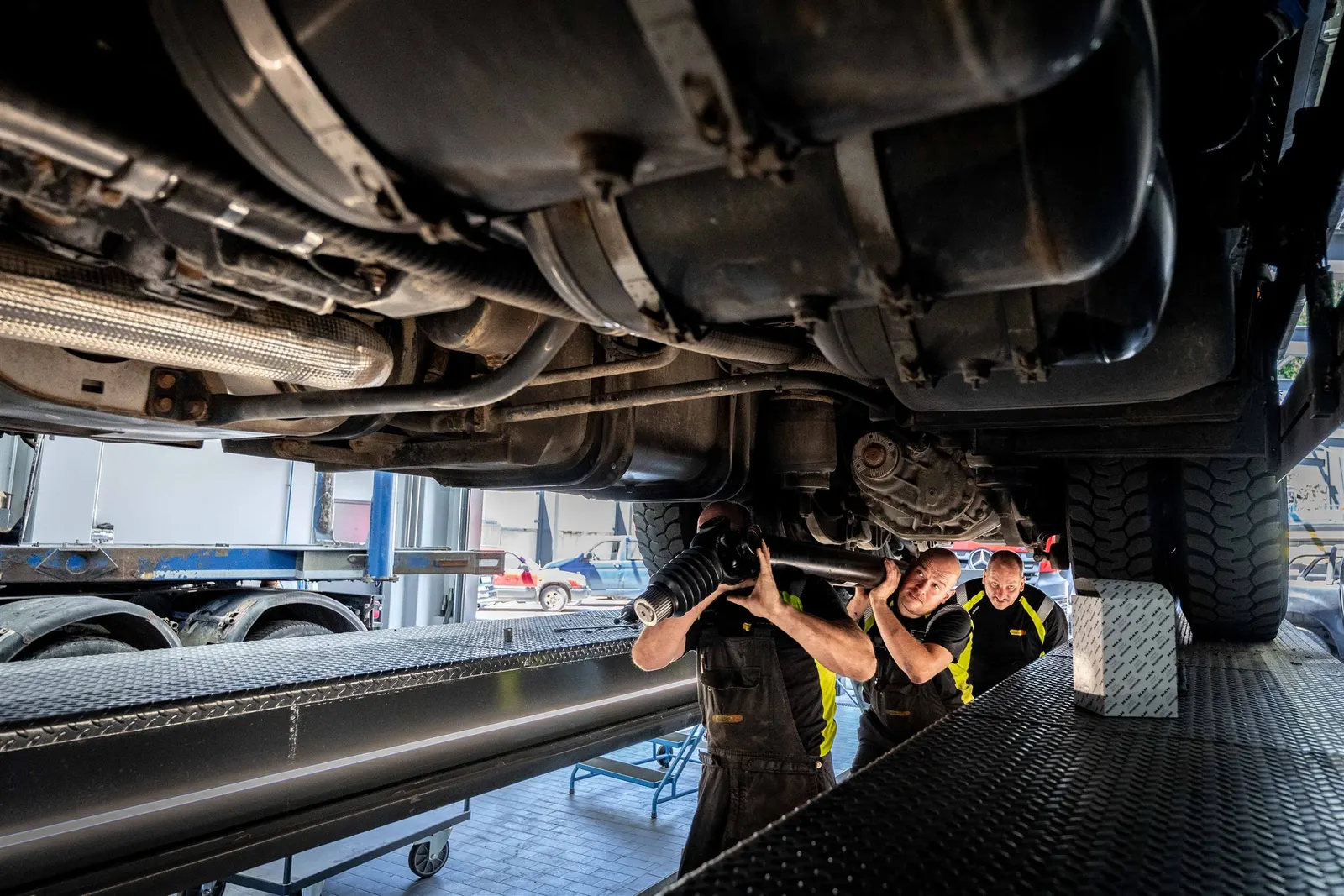 Mechaniker setzen eine Gelenkwelle unter einem Nutzfahrzeug ein